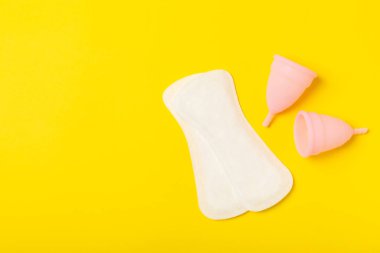 Aybaşı bardağı parlak bir arka planda. Hijyenik peçeteler, tamponlar ve regl kupası. Kritik günler, regl dönemi kavramı. Kadın hijyen ürünü. Kadın sağlığı kavramı. Adet öncesi sendromu. Boşluğu kopyala