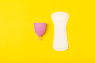 Aybaşı bardağı parlak bir arka planda. Hijyenik peçeteler, tamponlar ve regl kupası. Kritik günler, regl dönemi kavramı. Kadın hijyen ürünü. Kadın sağlığı kavramı. Adet öncesi sendromu. Boşluğu kopyala