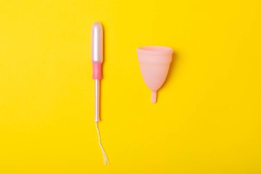 Aybaşı bardağı parlak bir arka planda. Hijyenik peçeteler, tamponlar ve regl kupası. Kritik günler, regl dönemi kavramı. Kadın hijyen ürünü. Kadın sağlığı kavramı. Adet öncesi sendromu. Boşluğu kopyala