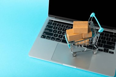 Çevrimiçi alışveriş kavramı. Karton kutu ve parlak renkli bir arka planda tramvayda alışveriş poşetleri. Alışveriş sepeti. İnternetten bilgisayar, tablet, telefon ve kredi kartı kullanarak alışveriş. Eve teslim.