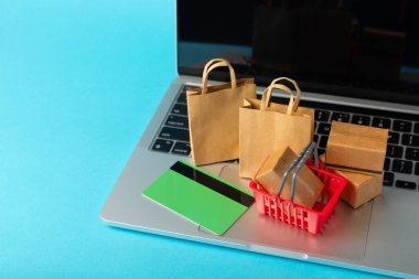 Çevrimiçi alışveriş kavramı. Karton kutu ve parlak renkli bir arka planda tramvayda alışveriş poşetleri. Alışveriş sepeti. İnternetten bilgisayar, tablet, telefon ve kredi kartı kullanarak alışveriş. Eve teslim.