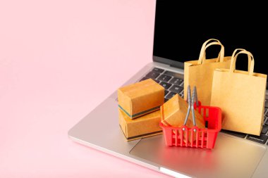 Çevrimiçi alışveriş kavramı. Karton kutu ve parlak renkli bir arka planda tramvayda alışveriş poşetleri. Alışveriş sepeti. İnternetten bilgisayar, tablet, telefon ve kredi kartı kullanarak alışveriş. Eve teslim.