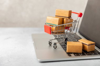 Çevrimiçi alışveriş kavramı. Karton kutu ve parlak renkli bir arka planda tramvayda alışveriş poşetleri. Alışveriş sepeti. İnternetten bilgisayar, tablet, telefon ve kredi kartı kullanarak alışveriş. Eve teslim.