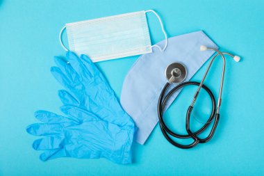 Tıbbi nitril eldivenler, mavi başlık, desenli arka planda tek kullanımlık tıbbi maske. Tıbbi koruyucu giysi. Cerrahi lateks eldivenler. Lastik eldiven üretimi. Tıp konsepti. Üst Manzara. Metni kopyala