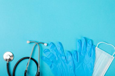 Tıbbi nitril eldivenler, mavi başlık, desenli arka planda tek kullanımlık tıbbi maske. Tıbbi koruyucu giysi. Cerrahi lateks eldivenler. Lastik eldiven üretimi. Tıp konsepti. Üst Manzara. Metni kopyala