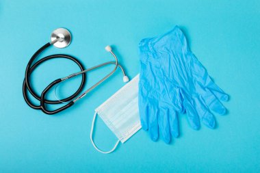 Tıbbi nitril eldivenler, mavi başlık, desenli arka planda tek kullanımlık tıbbi maske. Tıbbi koruyucu giysi. Cerrahi lateks eldivenler. Lastik eldiven üretimi. Tıp konsepti. Üst Manzara. Metni kopyala