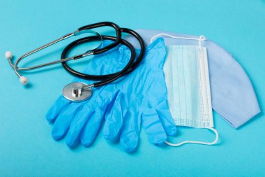 Tıbbi nitril eldivenler, mavi başlık, desenli arka planda tek kullanımlık tıbbi maske. Tıbbi koruyucu giysi. Cerrahi lateks eldivenler. Lastik eldiven üretimi. Tıp konsepti. Üst Manzara. Metni kopyala