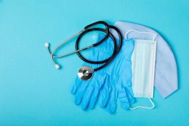 Tıbbi nitril eldivenler, mavi başlık, desenli arka planda tek kullanımlık tıbbi maske. Tıbbi koruyucu giysi. Cerrahi lateks eldivenler. Lastik eldiven üretimi. Tıp konsepti. Üst Manzara. Metni kopyala
