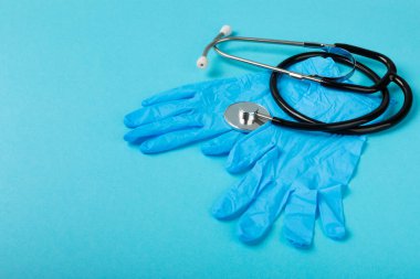 Tıbbi nitril eldivenler, mavi başlık, desenli arka planda tek kullanımlık tıbbi maske. Tıbbi koruyucu giysi. Cerrahi lateks eldivenler. Lastik eldiven üretimi. Tıp konsepti. Üst Manzara. Metni kopyala