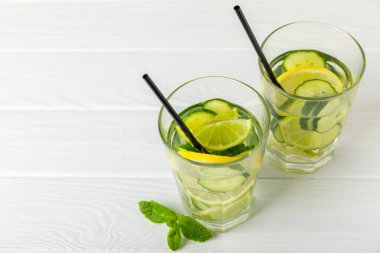 Salatalık suyu, limon, nane ve ahşap bir masada. İçme bardağında dilimlenmiş salatalık ile karıştırılmış su. Tonik ferahlatıcı bir içecek. Salatalık limonata. Doğal soğutma içeceği. Boşluğu kopyala.