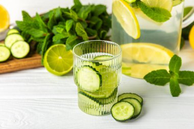 Salatalık suyu, limon, nane ve ahşap bir masada. İçme bardağında dilimlenmiş salatalık ile karıştırılmış su. Tonik ferahlatıcı bir içecek. Salatalık limonata. Doğal soğutma içeceği. Boşluğu kopyala.
