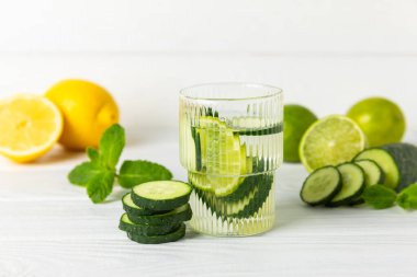 Salatalık suyu, limon, nane ve ahşap bir masada. İçme bardağında dilimlenmiş salatalık ile karıştırılmış su. Tonik ferahlatıcı bir içecek. Salatalık limonata. Doğal soğutma içeceği. Boşluğu kopyala.