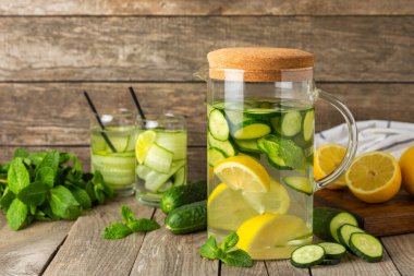 Salatalık suyu, limon, nane ve ahşap bir masada. İçme bardağında dilimlenmiş salatalık ile karıştırılmış su. Tonik ferahlatıcı bir içecek. Salatalık limonata. Doğal soğutma içeceği. Boşluğu kopyala.