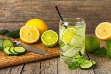 Salatalık suyu, limon, nane ve ahşap bir masada. İçme bardağında dilimlenmiş salatalık ile karıştırılmış su. Tonik ferahlatıcı bir içecek. Salatalık limonata. Doğal soğutma içeceği. Boşluğu kopyala.