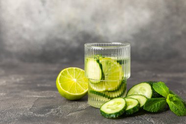 Salatalık suyu, limon, nane ve ahşap bir masada. İçme bardağında dilimlenmiş salatalık ile karıştırılmış su. Tonik ferahlatıcı bir içecek. Salatalık limonata. Doğal soğutma içeceği. Boşluğu kopyala.