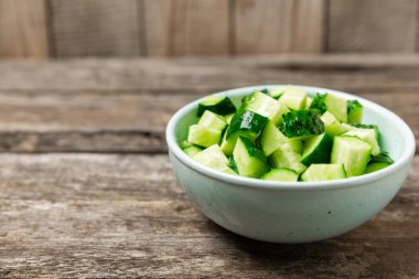 Ahşap arka planda salatalık. Arka planda bir parça salatalık. Taze organik yeşil salatalık turşusu. Vejetaryen. Salata malzemesi. Çiftlik sebzeleri. Sebzeleri bıçakla kes. Mesaj için yer var. Boşluğu kopyala