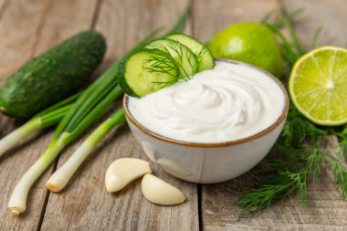 Ahşap bir masada salatalık kremalı tzatziki sosu. Tatar sosu. Geleneksel lezzetli aperatif. Yoğurt sosu. Tzatziki, salatalık, sarımsak, dereotu, limon, nane. Salata sosu. Kopya alanı.