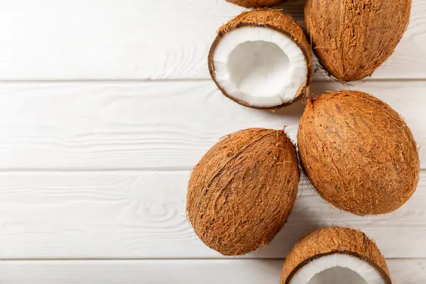 Tahta arka planda taze hindistan cevizi ve dilimler var. Hindistan cevizi gevreği. Vejetaryen. Tropik fındık, meyve. Mesaj için yer. Boşluğu kopyala.