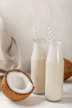 Bir şişe lezzetli hindistan cevizi sütü dokulu arka planda. Hindistan cevizli yoğurt ve hindistan cevizi. Vejetaryen çevre dostu ürün. Metin için boşluk. Boşluğu kopyala.