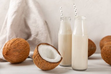 Bir şişe lezzetli hindistan cevizi sütü dokulu arka planda. Hindistan cevizli yoğurt ve hindistan cevizi. Vejetaryen çevre dostu ürün. Metin için boşluk. Boşluğu kopyala.