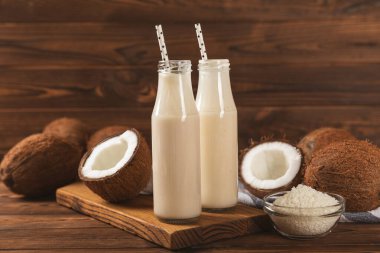 Bir şişe lezzetli hindistan cevizi sütü dokulu arka planda. Hindistan cevizli yoğurt ve hindistan cevizi. Vejetaryen çevre dostu ürün. Metin için boşluk. Boşluğu kopyala.