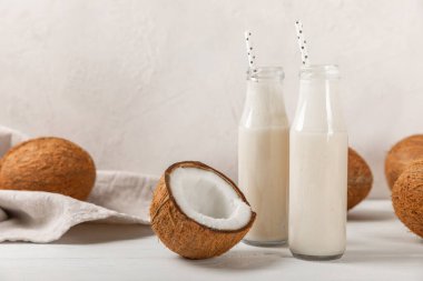 Bir şişe lezzetli hindistan cevizi sütü dokulu arka planda. Hindistan cevizli yoğurt ve hindistan cevizi. Vejetaryen çevre dostu ürün. Metin için boşluk. Boşluğu kopyala.