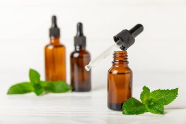 Ahşap bir arka planda esaslı bir nane şekeri. Naneli esaslı yağ ve taze nane yaprakları. Bir şişe aromaterapi yağı. Nane özütü. Doğal kozmetik konsepti, spa bakımı. Boşluğu kopyala