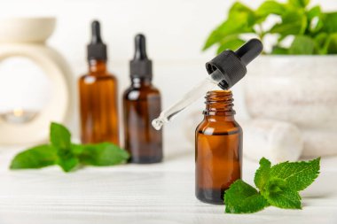 Ahşap bir arka planda esaslı bir nane şekeri. Naneli esaslı yağ ve taze nane yaprakları. Bir şişe aromaterapi yağı. Nane özütü. Doğal kozmetik konsepti, spa bakımı. Boşluğu kopyala