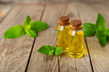 Ahşap bir arka planda esaslı bir nane şekeri. Naneli esaslı yağ ve taze nane yaprakları. Bir şişe aromaterapi yağı. Nane özütü. Doğal kozmetik konsepti, spa bakımı. Boşluğu kopyala