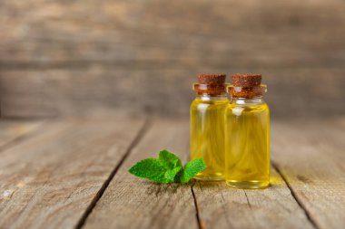 Ahşap bir arka planda esaslı bir nane şekeri. Naneli esaslı yağ ve taze nane yaprakları. Bir şişe aromaterapi yağı. Nane özütü. Doğal kozmetik konsepti, spa bakımı. Boşluğu kopyala