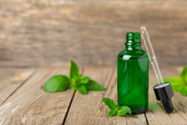 Ahşap bir arka planda esaslı bir nane şekeri. Naneli esaslı yağ ve taze nane yaprakları. Bir şişe aromaterapi yağı. Nane özütü. Doğal kozmetik konsepti, spa bakımı. Boşluğu kopyala