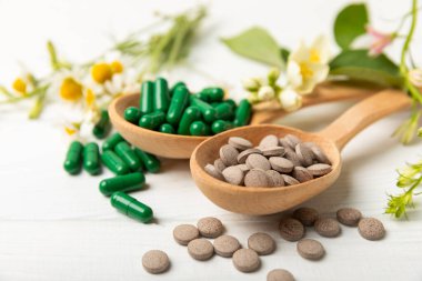 Ahşap zemin üzerinde alternatif ilaç bitkisel kapsül organik ilaç. Bitki ve tablet çeşitleri, vitaminler ve diyet takviyeleri. Sağlıklı yaşam için tıbbi ve şifalı bitkiler.