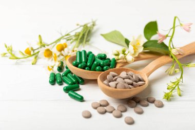 Ahşap zemin üzerinde alternatif ilaç bitkisel kapsül organik ilaç. Bitki ve tablet çeşitleri, vitaminler ve diyet takviyeleri. Sağlıklı yaşam için tıbbi ve şifalı bitkiler.