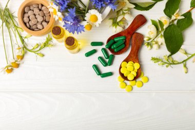 Ahşap zemin üzerinde alternatif ilaç bitkisel kapsül organik ilaç. Bitki ve tablet çeşitleri, vitaminler ve diyet takviyeleri. Sağlıklı yaşam için tıbbi ve şifalı bitkiler.