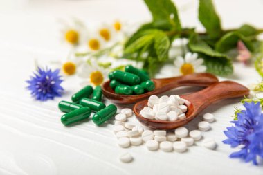 Ahşap zemin üzerinde alternatif ilaç bitkisel kapsül organik ilaç. Bitki ve tablet çeşitleri, vitaminler ve diyet takviyeleri. Sağlıklı yaşam için tıbbi ve şifalı bitkiler.