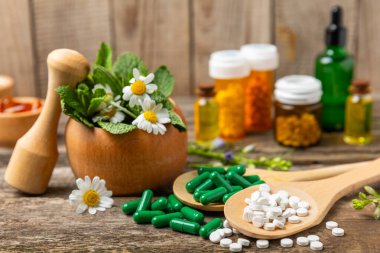 Ahşap zemin üzerinde alternatif ilaç bitkisel kapsül organik ilaç. Bitki ve tablet çeşitleri, vitaminler ve diyet takviyeleri. Sağlıklı yaşam için tıbbi ve şifalı bitkiler.
