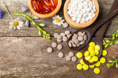 Ahşap zemin üzerinde alternatif ilaç bitkisel kapsül organik ilaç. Bitki ve tablet çeşitleri, vitaminler ve diyet takviyeleri. Sağlıklı yaşam için tıbbi ve şifalı bitkiler.