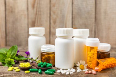 Ahşap zemin üzerinde alternatif ilaç bitkisel kapsül organik ilaç. Bitki ve tablet çeşitleri, vitaminler ve diyet takviyeleri. Sağlıklı yaşam için tıbbi ve şifalı bitkiler.