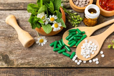 Ahşap zemin üzerinde alternatif ilaç bitkisel kapsül organik ilaç. Bitki ve tablet çeşitleri, vitaminler ve diyet takviyeleri. Sağlıklı yaşam için tıbbi ve şifalı bitkiler.