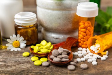 Ahşap zemin üzerinde alternatif ilaç bitkisel kapsül organik ilaç. Bitki ve tablet çeşitleri, vitaminler ve diyet takviyeleri. Sağlıklı yaşam için tıbbi ve şifalı bitkiler.