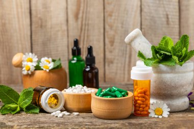 Ahşap zemin üzerinde alternatif ilaç bitkisel kapsül organik ilaç. Bitki ve tablet çeşitleri, vitaminler ve diyet takviyeleri. Sağlıklı yaşam için tıbbi ve şifalı bitkiler.