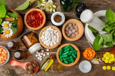 Ahşap zemin üzerinde alternatif ilaç bitkisel kapsül organik ilaç. Bitki ve tablet çeşitleri, vitaminler ve diyet takviyeleri. Sağlıklı yaşam için tıbbi ve şifalı bitkiler.