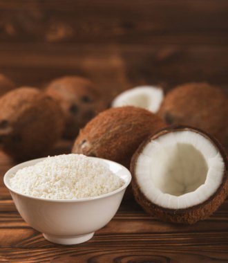 Tahta arka planda taze hindistan cevizi ve dilimler var. Hindistan cevizi gevreği. Vejetaryen. Tropik fındık, meyve. Mesaj için yer. Boşluğu kopyala.