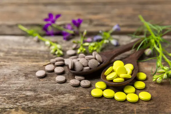 Ahşap zemin üzerinde alternatif ilaç bitkisel kapsül organik ilaç. Bitki ve tablet çeşitleri, vitaminler ve diyet takviyeleri. Sağlıklı yaşam için tıbbi ve şifalı bitkiler.