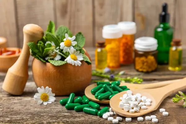 Ahşap zemin üzerinde alternatif ilaç bitkisel kapsül organik ilaç. Bitki ve tablet çeşitleri, vitaminler ve diyet takviyeleri. Sağlıklı yaşam için tıbbi ve şifalı bitkiler.