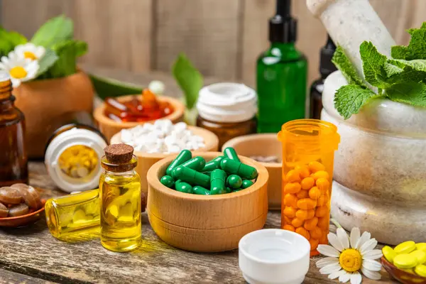 Ahşap zemin üzerinde alternatif ilaç bitkisel kapsül organik ilaç. Bitki ve tablet çeşitleri, vitaminler ve diyet takviyeleri. Sağlıklı yaşam için tıbbi ve şifalı bitkiler.