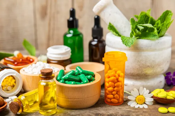 Ahşap zemin üzerinde alternatif ilaç bitkisel kapsül organik ilaç. Bitki ve tablet çeşitleri, vitaminler ve diyet takviyeleri. Sağlıklı yaşam için tıbbi ve şifalı bitkiler.