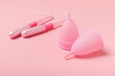 Aybaşı bardağı parlak bir arka planda. Hijyenik peçeteler, tamponlar ve regl kupası. Kritik günler, regl dönemi kavramı. Kadın hijyen ürünü. Kadın sağlığı kavramı. Adet öncesi sendromu. Boşluğu kopyala