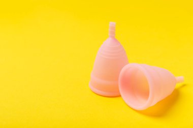 Aybaşı bardağı parlak bir arka planda. Hijyenik peçeteler, tamponlar ve regl kupası. Kritik günler, regl dönemi kavramı. Kadın hijyen ürünü. Kadın sağlığı kavramı. Adet öncesi sendromu. Boşluğu kopyala