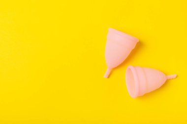 Aybaşı bardağı parlak bir arka planda. Hijyenik peçeteler, tamponlar ve regl kupası. Kritik günler, regl dönemi kavramı. Kadın hijyen ürünü. Kadın sağlığı kavramı. Adet öncesi sendromu. Boşluğu kopyala